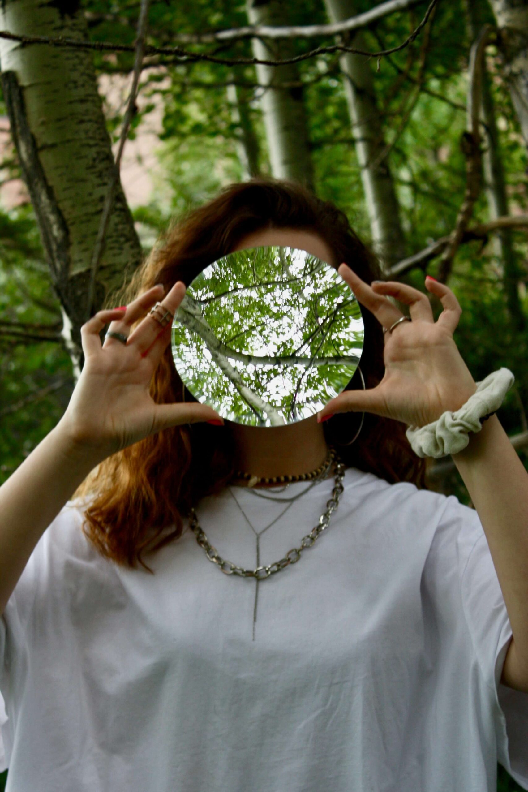 woman holding mirror in forest while microdosing